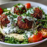 A vibrant falafel bowl features creamy hummus, tangy tzatziki, and colorful vegetables for lunch.