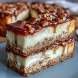 Creamy carrot cake cheesecake bars with a marbled swirl of spiced cake and vanilla cheesecake filling.