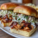 Savory shredded BBQ chicken piled high on slider buns, topped with crisp, colorful coleslaw for a summer feast.
