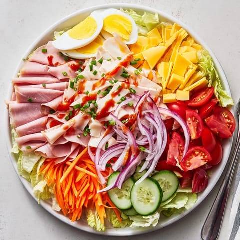 Freshly prepared Chef Salad with crisp romaine and iceberg lettuce, colorful tomato wedges, cucumber slices, and julienned carrots, ready to serve as a hearty main dish.