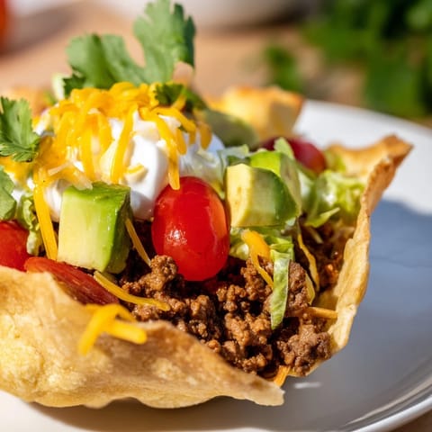 A loaded Taco Salad topped with melted cheddar, creamy sour cream, and vibrant fresh salsa.