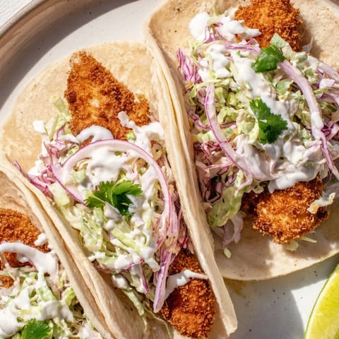 Freshly grilled Fish Tacos packed with flaky white fish, shredded cabbage, and cilantro, drizzled with creamy sauce and lime.