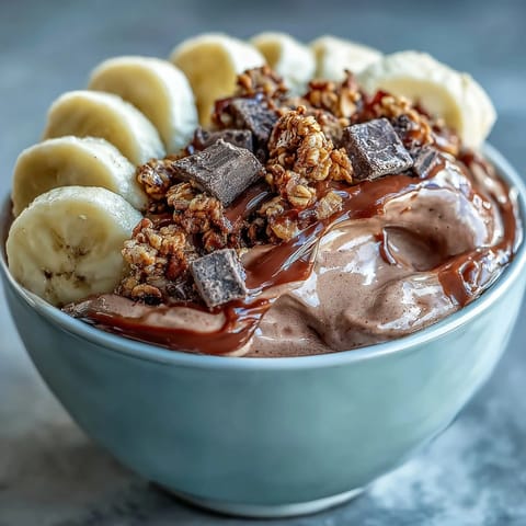 A thick, creamy Chocolate Peanut Butter Smoothie Bowl topped with banana slices, granola, and a rich peanut butter drizzle.