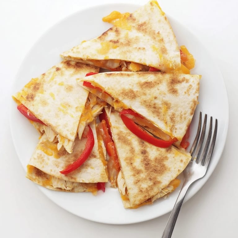 Close-up of a slice of Chicken Quesadilla being pulled apart, showcasing the steamy, cheesy filling with red peppers and onions.