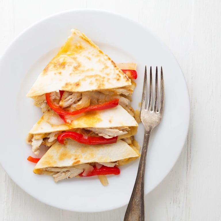 Grilled chicken and sautéed bell peppers nestled inside a toasted flour tortilla, served with a side of creamy guacamole.