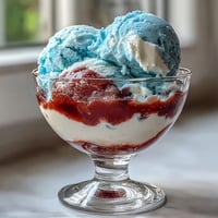 Red, White, and Blue Layered Jello Cups in clear glasses, vibrant stripes of cherry, creamy white, and blue raspberry Jello.