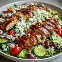 Greek Salad Bowl with Grilled Chicken topped with feta and Kalamata olives, perfect for a healthy summer lunch or dinner.  