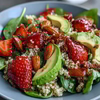 A vibrant strawberry avocado quinoa salad with fresh greens, juicy berries, and creamy avocado in a citrus dressing.  