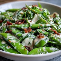 Crisp snap pea and radish salad with creamy tahini dressing, perfect for a refreshing spring lunch.  